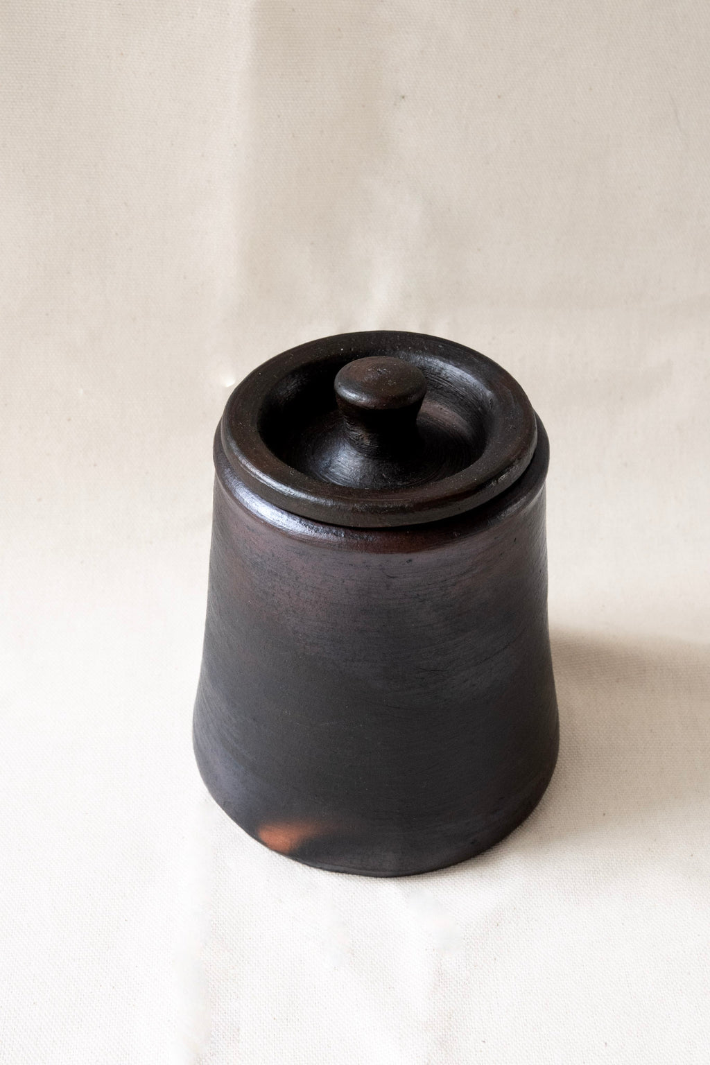 Black ceramic jar with lid on a white background