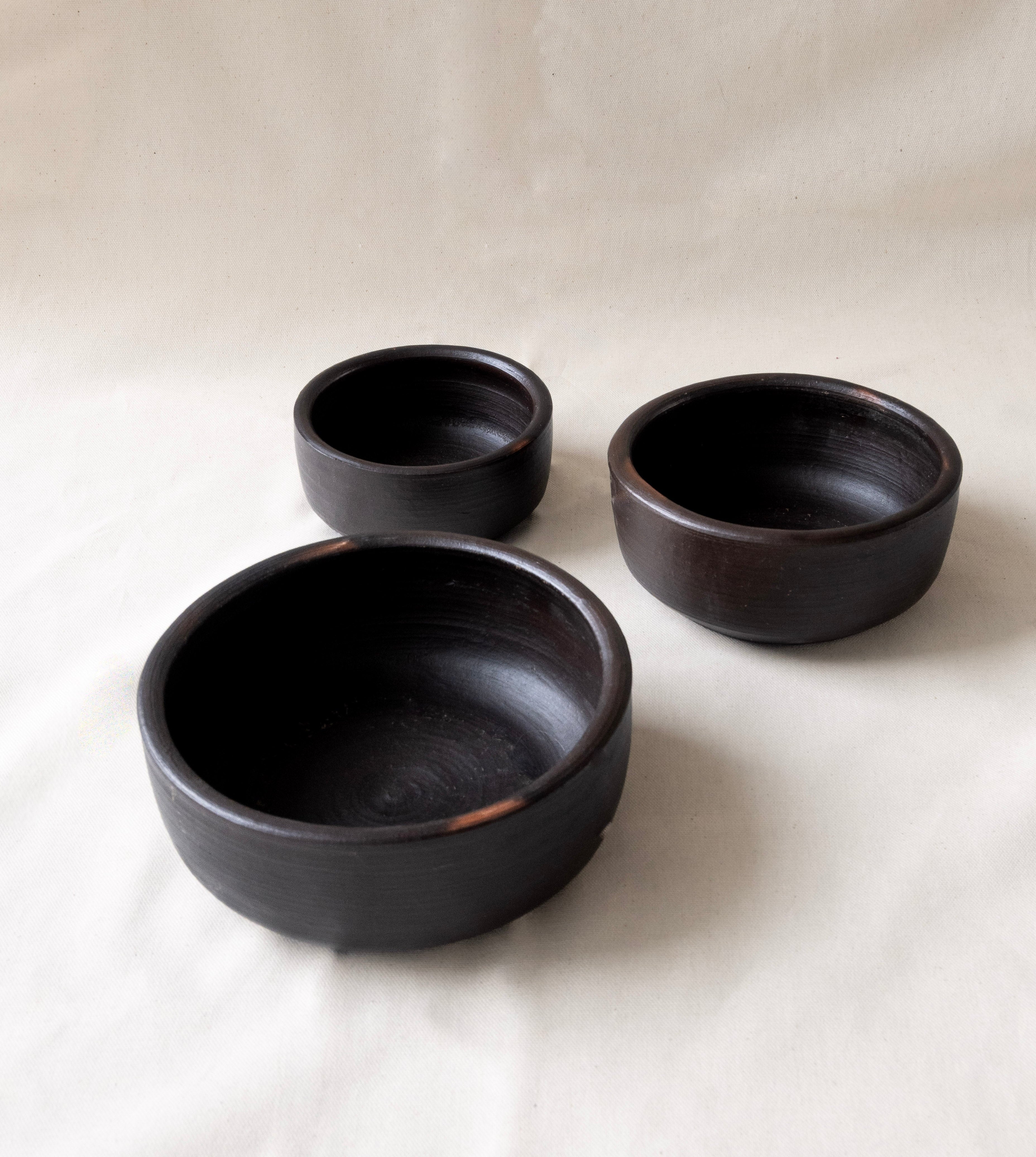 Three black ceramic bowls on a white background