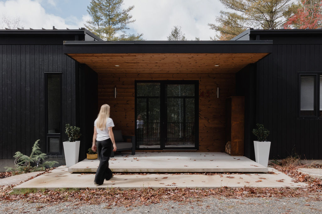 Photo of a model walking toward a  modern house with a wooden porch